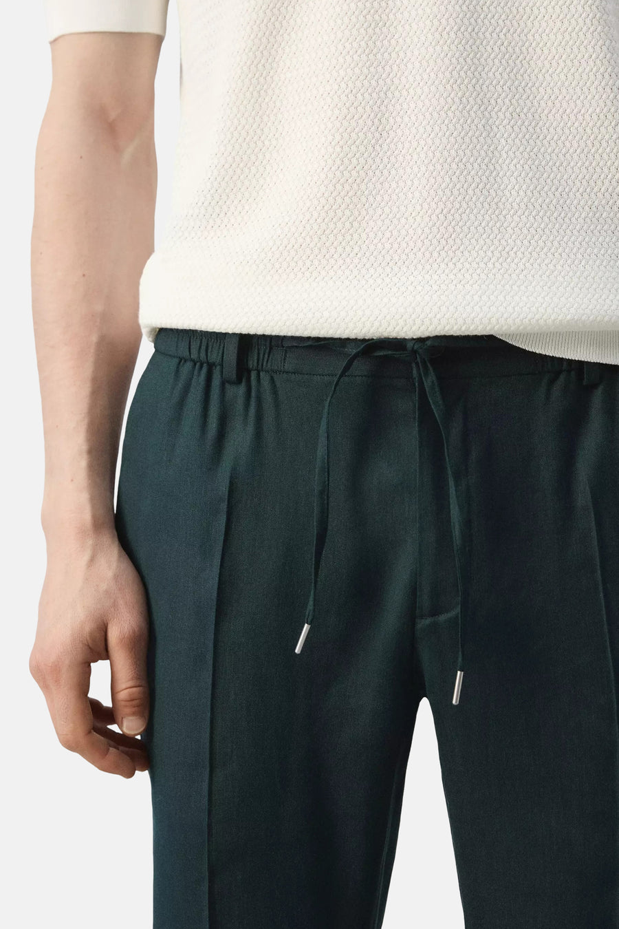 Groene broek van MANGO met trekkoord taille, zilveren aglets en gedragen met een wit gestructureerd T-shirt.