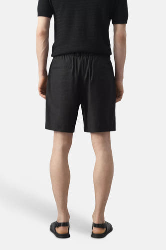 Zwarte Bermuda's van MANGO, achterkant, met elastische taille en twee achterzakken, gedragen met zwart shirt en sandalen