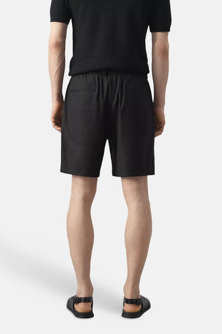 Zwarte Bermuda's van MANGO, achterkant, met elastische taille en twee achterzakken, gedragen met zwart shirt en sandalen