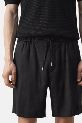 Zwarte Bermuda's van MANGO met elastische tailleband en trekkoord, voorzien van zilveren metalen tips en zakken, vooraanzicht op model