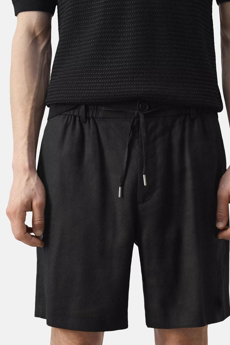Zwarte Bermuda's van MANGO met elastische tailleband en trekkoord, voorzien van zilveren metalen tips en zakken, vooraanzicht op model