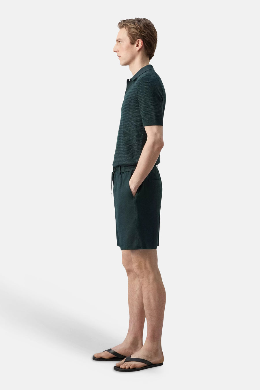 Groene Bermuda's van MANGO, zijprofiel, met elastische tailleband en zak, gedragen met donkergroen poloshirt en zwarte slippers