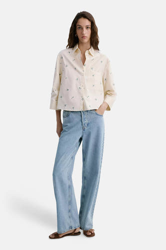 Crèmekleurige blouse met lange mouwen en kleine groene bloemenprint van MANGO, met borstzakje, gedragen met lichtblauwe jeans en bruine sandalen, front view.