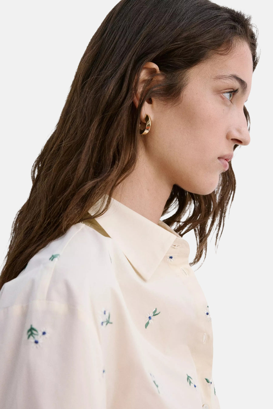 Crèmekleurige blouse met lange mouwen en bloemen borduurwerk van MANGO, zijwaarts gezien, met gouden oorbellen