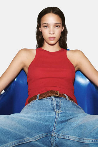 Lichtblauwe mom jeans van MANGO, met hoge taille en wijde pijpen, gedragen met rode tanktop en bruine gevlochten riem, lifestyle shot.