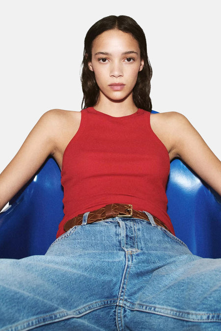 Lichtblauwe mom jeans van MANGO, met hoge taille en wijde pijpen, gedragen met rode tanktop en bruine gevlochten riem, lifestyle shot.