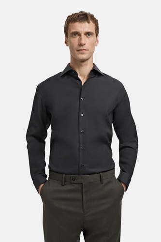 Zwart overhemd met lange mouwen van MANGO, met knoopsluiting en lange mouwen, gedragen met donkere pantalon.
