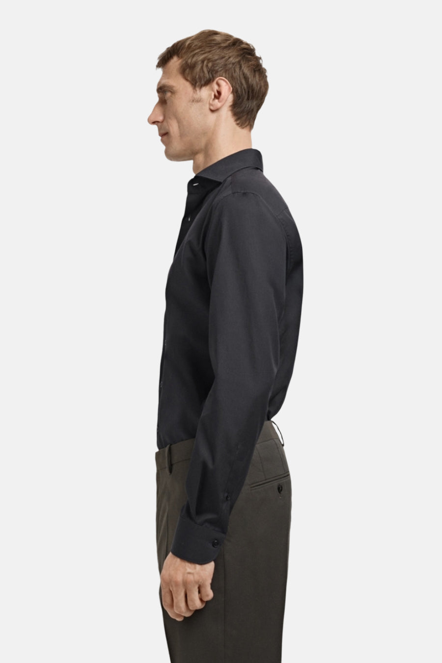 Man in zwart overhemd en groene broek, zijprofiel.
