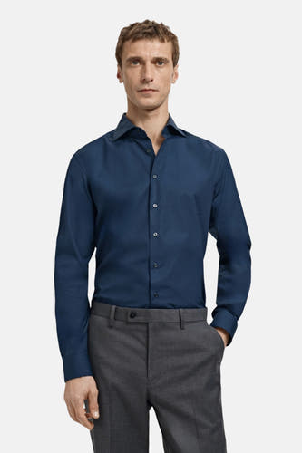 Blauw overhemd met lange mouwen van MANGO, gedragen met grijze pantalon.