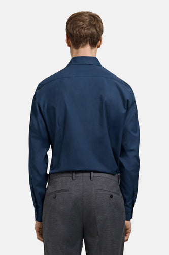 Man in blauw overhemd en grijze pantalon, achterkant.