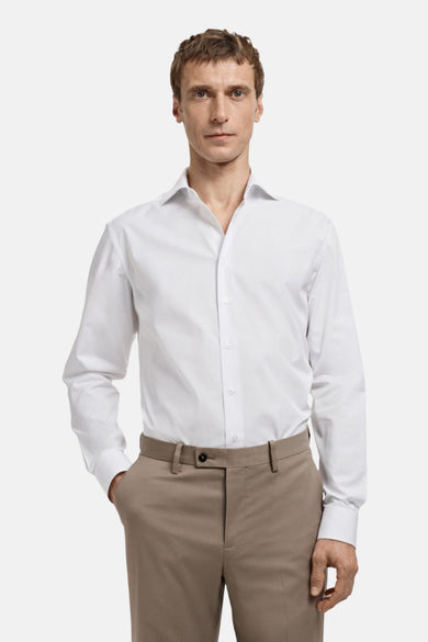 Blouse blanche à manches longues de MANGO, vue de derrière, associée à un pantalon marron.
