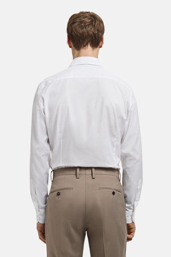 Man in witte overhemd en beige pantalon, achterkant.