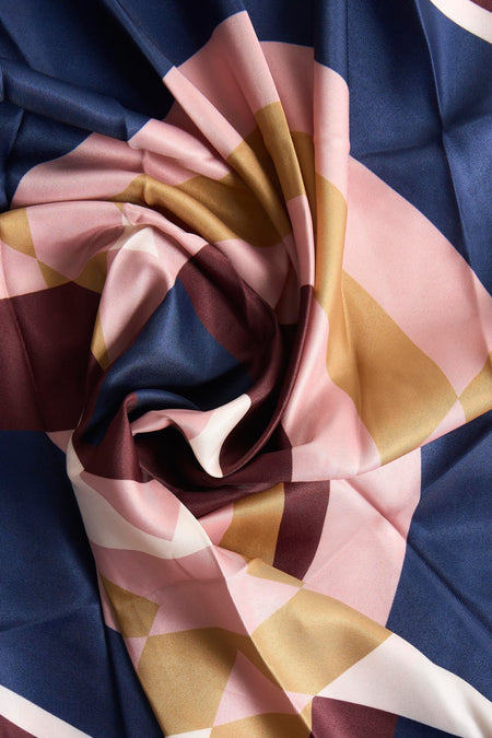 Multikleurige zomersjaal van MANGO met een geometrisch patroon in roze, goud, wit, bordeaux en marineblauw.