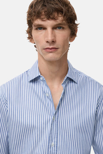 Chemise bleue rayée avec manches longues de MANGO, portée par un homme aux cheveux bruns.