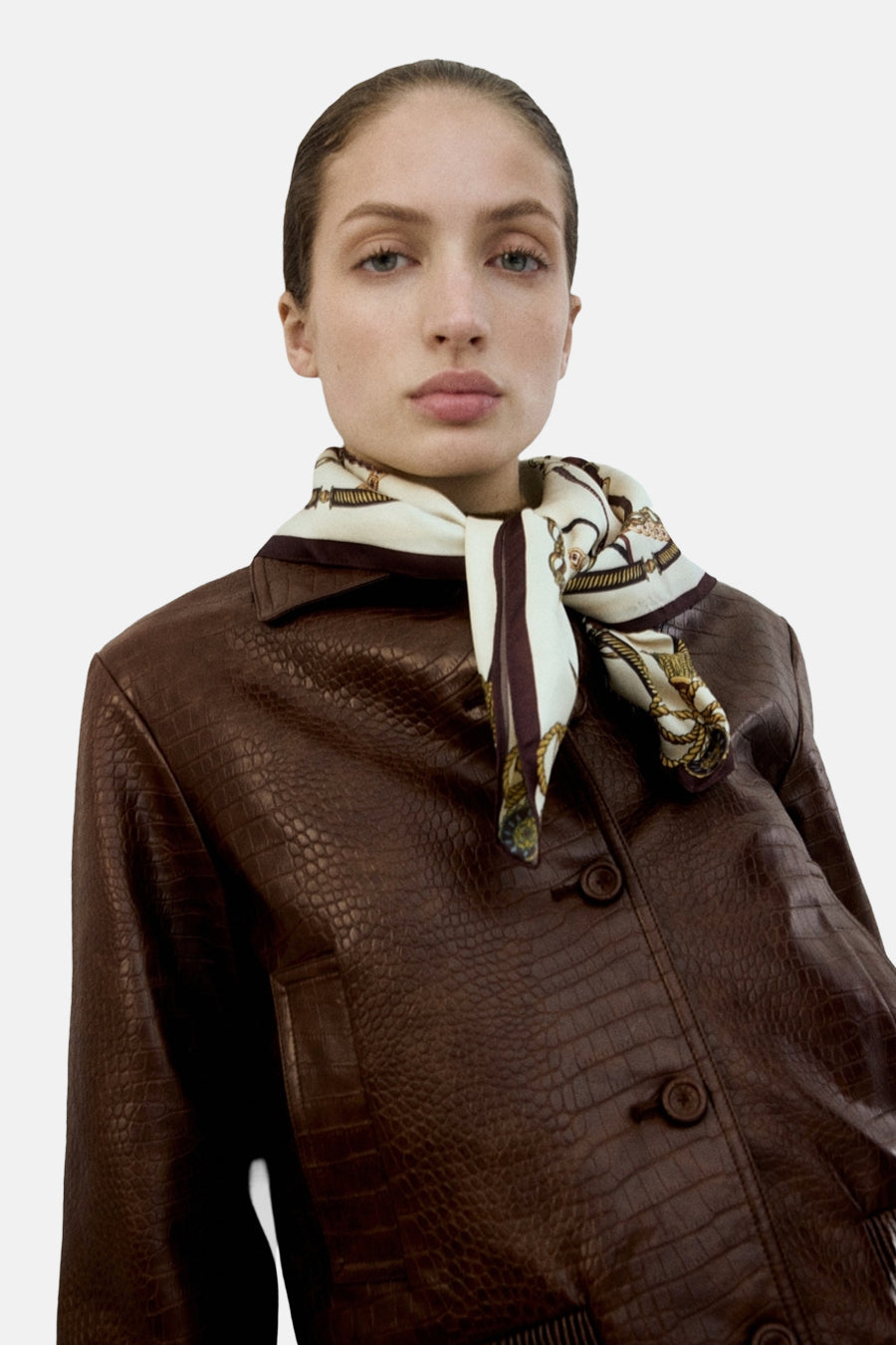 Bruine korte jas van MANGO met krokodillenpatroon, gedragen met een beige zijden sjaal om de hals.
