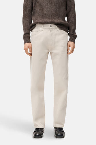 Jean droit en denim off-white de MANGO, avec des poches arrière, associé à une chemise brune et des chaussures noires, vu de dos.