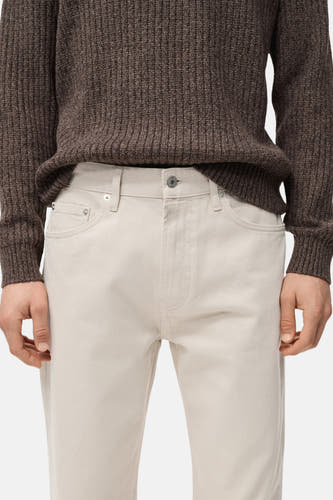 Jean droit blanc cassé de MANGO, associé à une chemise brune tricotée.