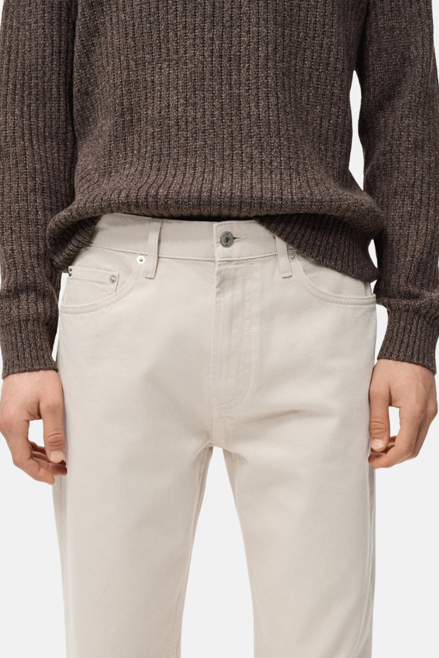 Jean droit blanc cassé de MANGO, associé à une chemise brune tricotée.