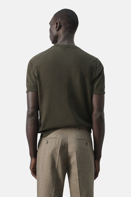 Kaki T-shirt met korte mouwen van MANGO, gezien van achteren, gecombineerd met een stoffen pantalon.
