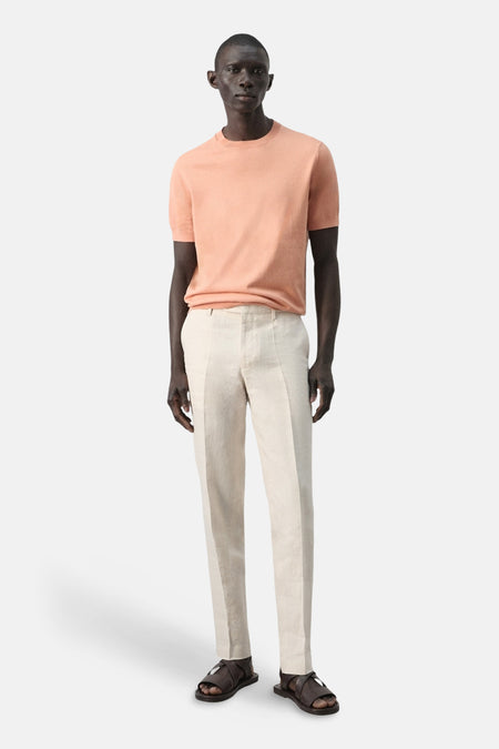 T-shirt à manches courtes orange de MANGO, porté avec un pantalon en lin de couleur crème et des sandales marron.