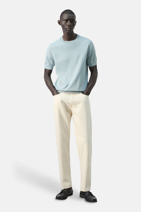 T-shirt bleu à manches courtes de MANGO, porté avec un pantalon beige et des chaussures noires.