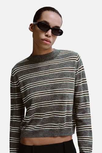 Pull gris à col rond de MANGO, avec des rayures horizontales marron et blanches, combiné avec un pantalon noir.