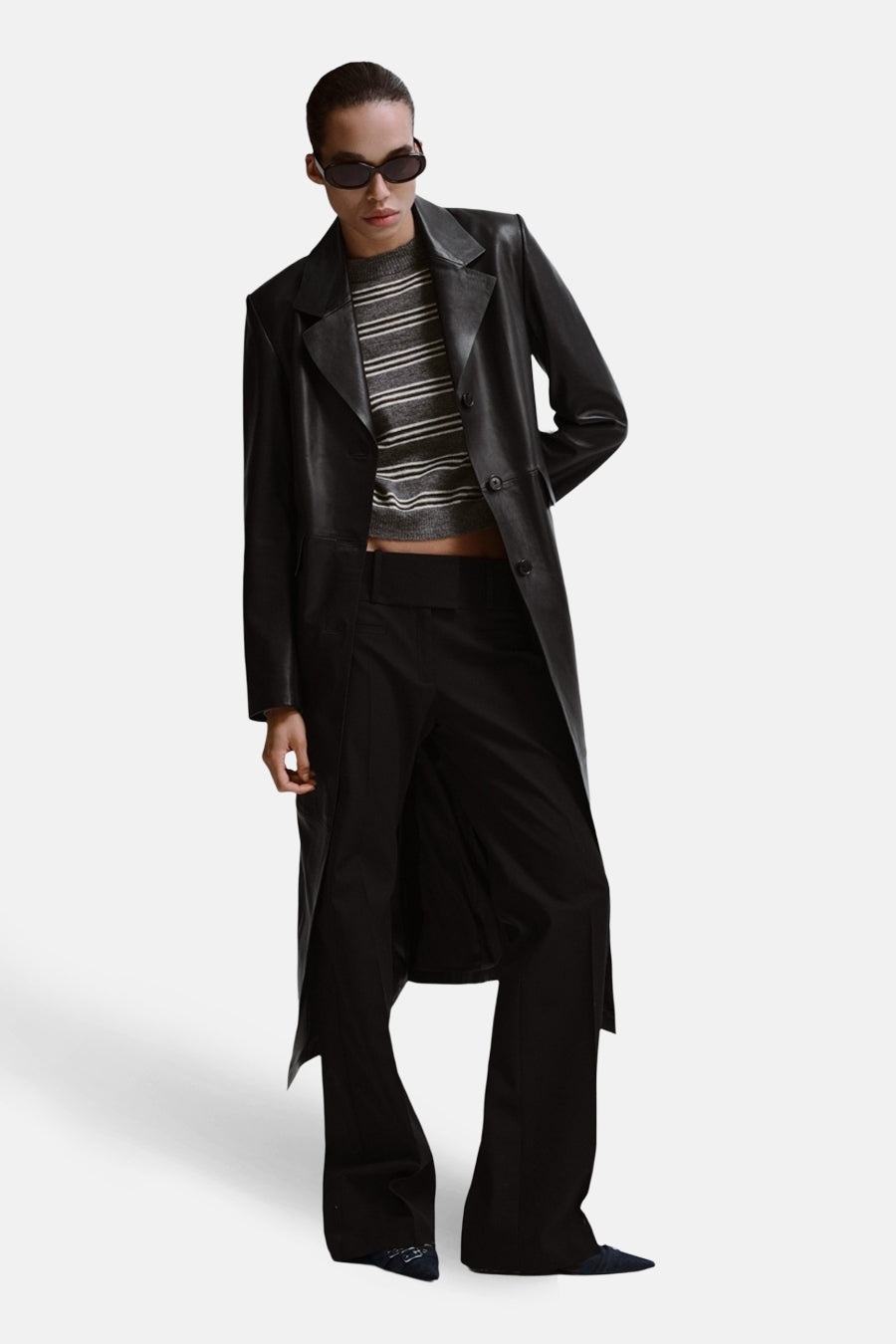 Pull gris à col rond de MANGO, à rayures horizontales, porté sous une veste et un pantalon en cuir noir.