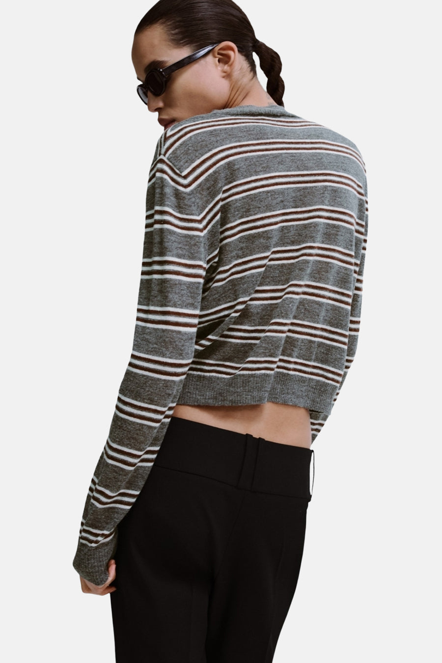 Grijze trui met ronde hals van MANGO, met bruine en witte horizontale strepen, gecombineerd met een zwarte broek.