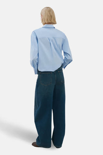 Blauw, langmouwig hemd van MANGO, gezien van achteren, gecombineerd met wijde jeans.