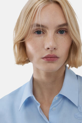 Blauw, lange mouwen overhemd van MANGO, close-up van een model met blonde bob en blauwe ogen.