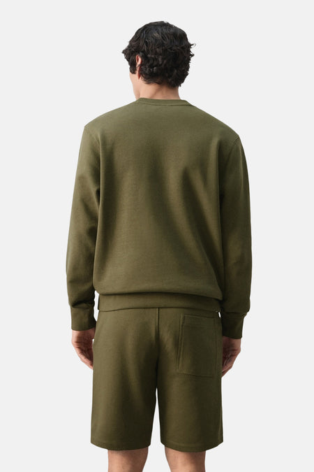 Khaki sweater met ronde hals van MANGO, achteraanzicht met bijpassende shorts.