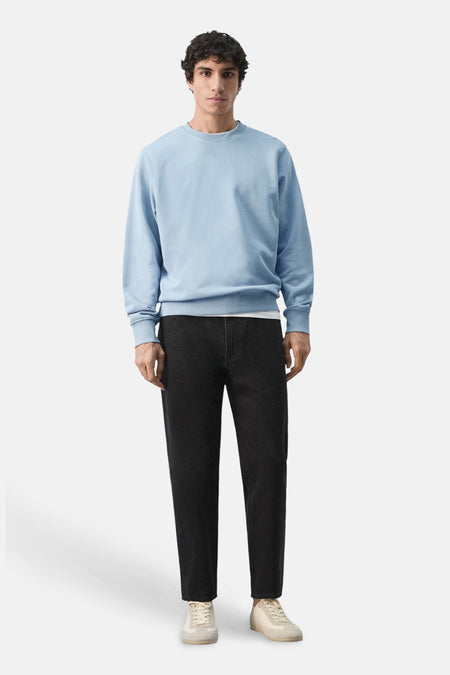 Pull bleu de MANGO, à manches longues, combiné avec un jean foncé et des baskets couleur crème.
