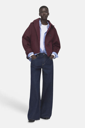 Bordeaux korte jas van MANGO, gedragen over een wit shirt met blauw gestreept overhemd en wijde, donkerblauwe jeans.
