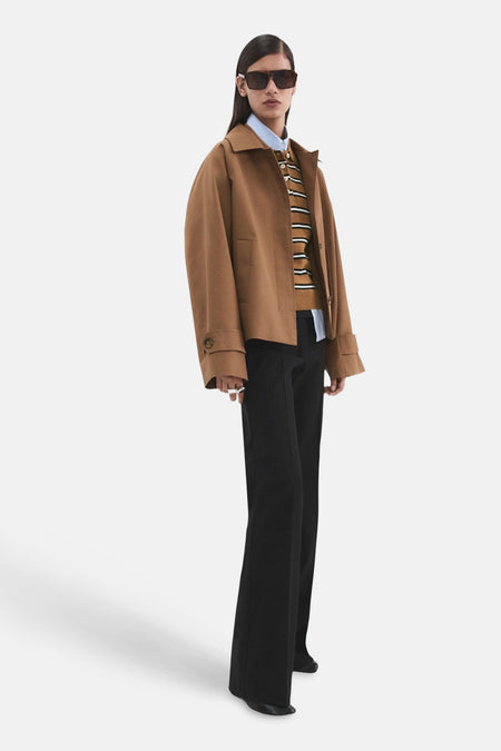 Polo multicolore à manches courtes de MANGO, à motif rayé et portée sous une veste marron et un pantalon noir.