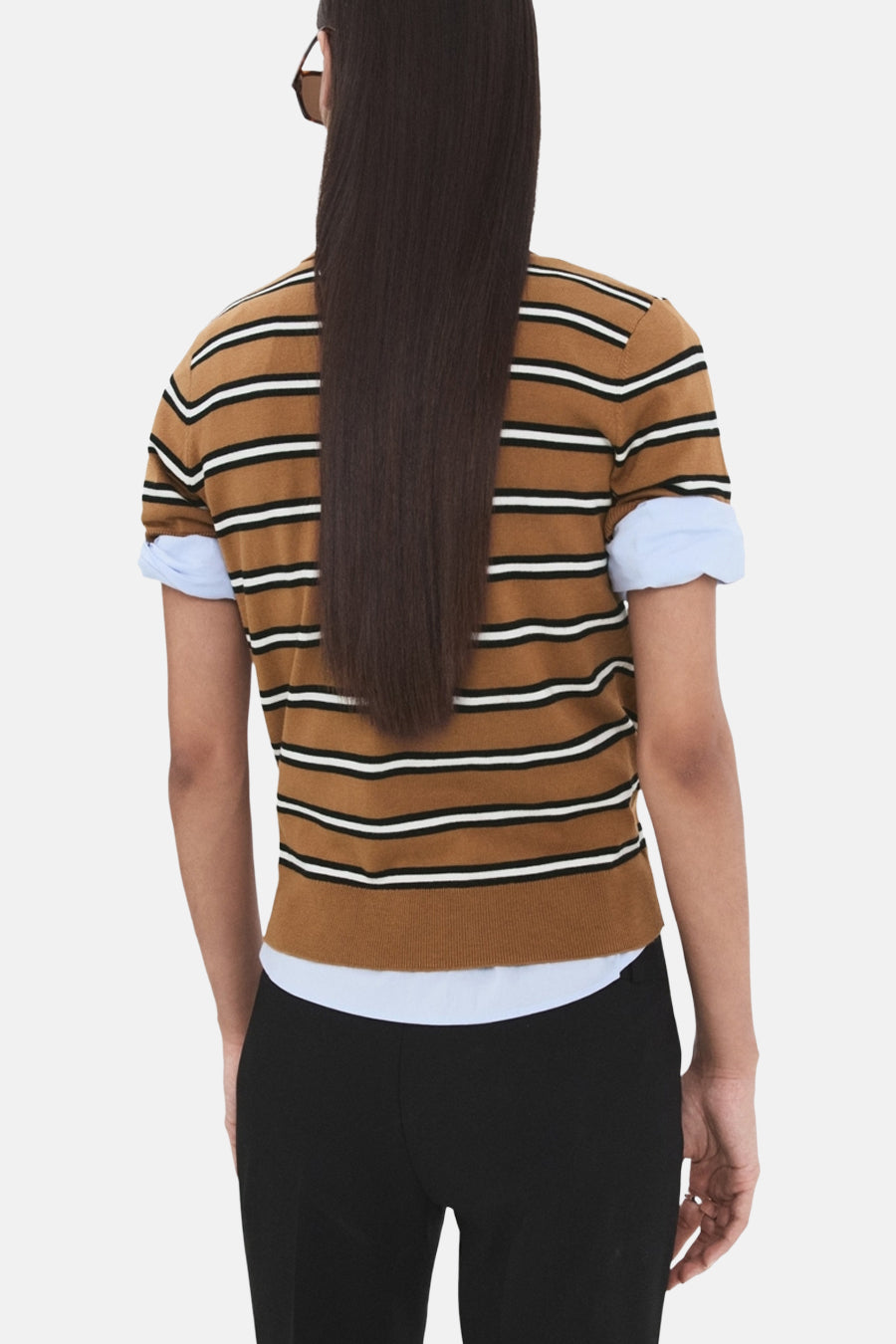 Veelkleurige polo met korte mouwen van MANGO, met een gestreept patroon, gedragen met zwarte pantalon.
