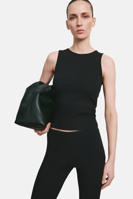 Débardeur noir de MANGO, montré de dos avec une queue de cheval et un legging noir avec une fente à l'ourlet.