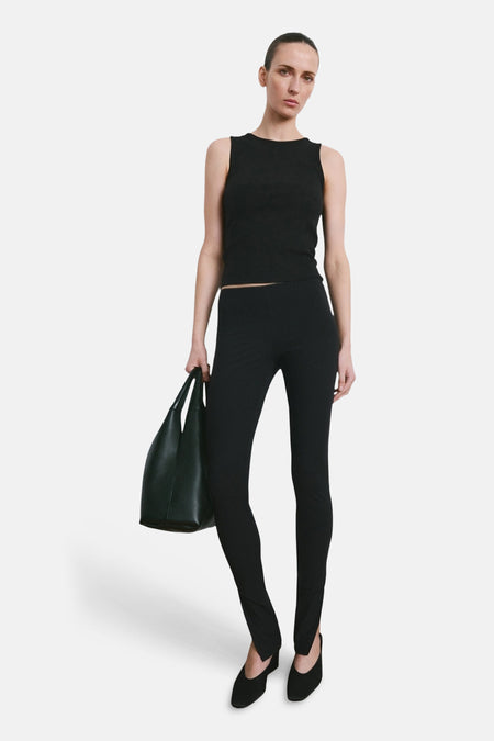 Débardeur noir de MANGO, porté avec un legging noir et des escarpins noirs, et un sac à main noir.
