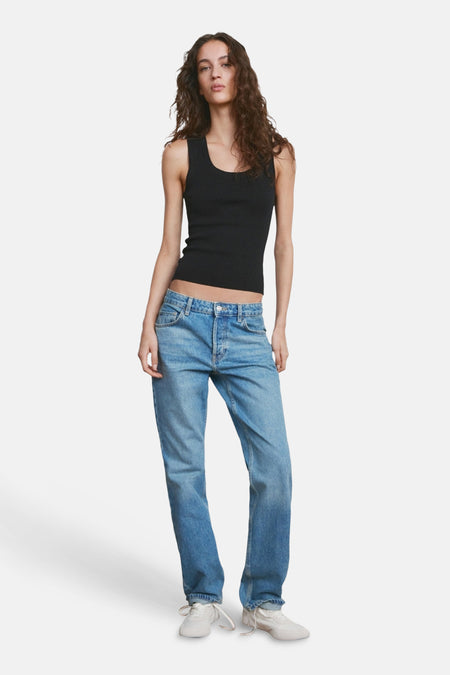 Haut noire de MANGO, avec une texture côtelée et combinée avec un jean bleu et des baskets blanches.