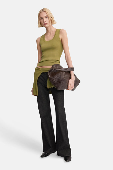 Débardeur kaki de MANGO, à la coupe ajustée, associé à un jean foncé ample et un sac tissé marron.