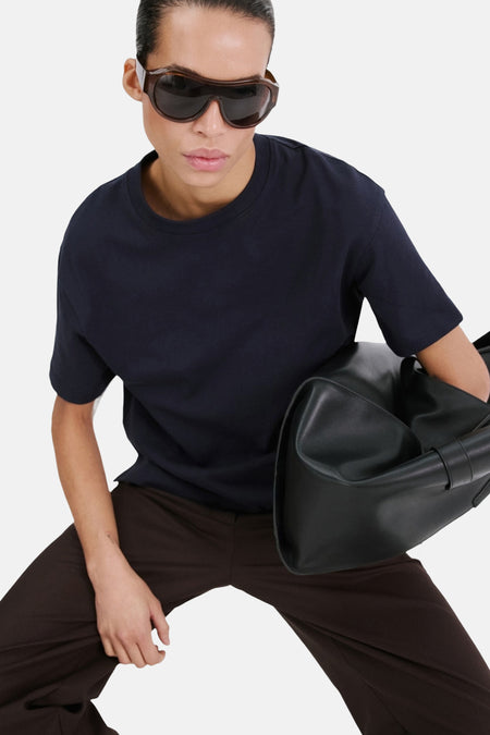 Blauw T-shirt van MANGO, met korte mouwen, gedragen met een bruine broek en zwarte zonnebril.
