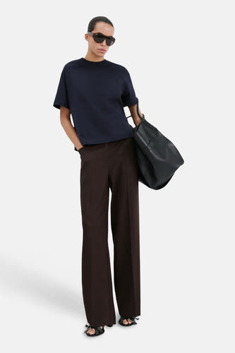 Blauw T-shirt met korte mouwen van MANGO, gecombineerd met een bruine pantalon, zwarte handtas en zwarte sandalen.