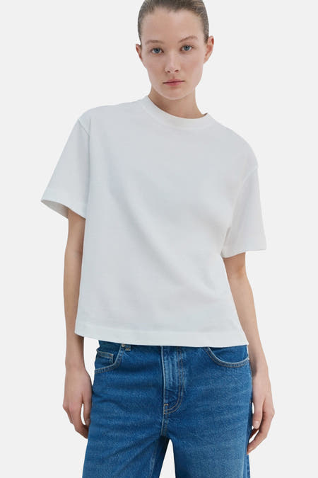 Wit T-shirt van MANGO, gedragen met blauwe jeans, effen stof.

