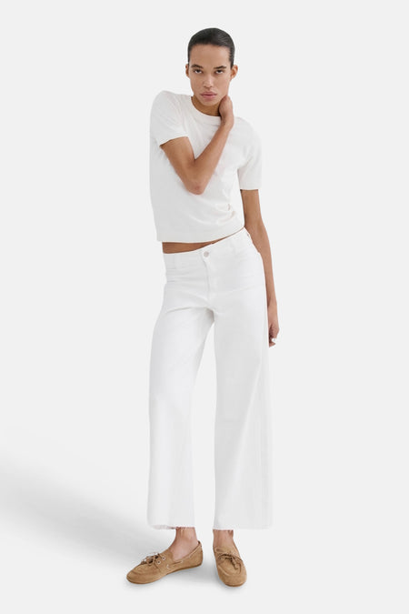 Witte wijde jeans van MANGO, gecombineerd met een wit shirt en bruine schoenen.
