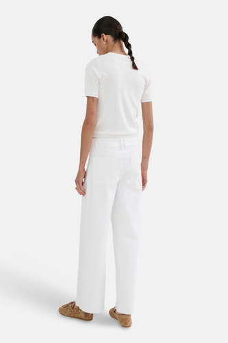 Witte wijde jeans van MANGO, gezien van achteren, gecombineerd met een crèmekleurig shirt en bruine mocassins.