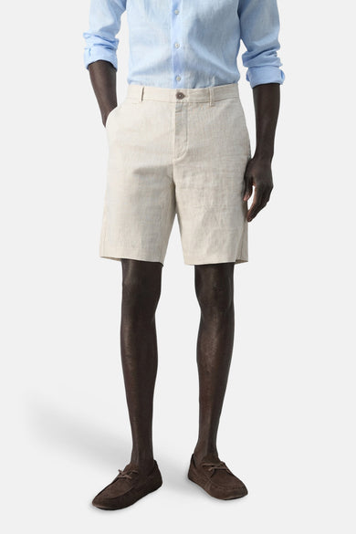 Beige bermuda van MANGO, gecombineerd met een lichtblauw overhemd en bruine mocassins.