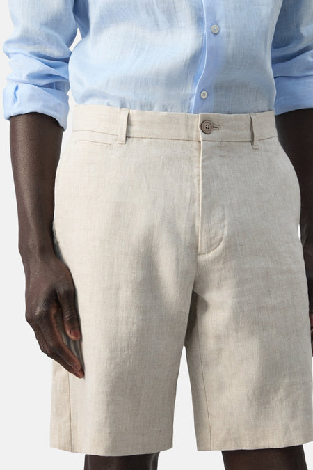 Beige bermuda van MANGO, met riemlussen en een knoopsluiting, gedragen met een lichtblauw overhemd.