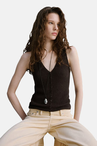 Haut marron sans manches de MANGO, vue de dos avec des cheveux bruns bouclés et un pantalon beige.