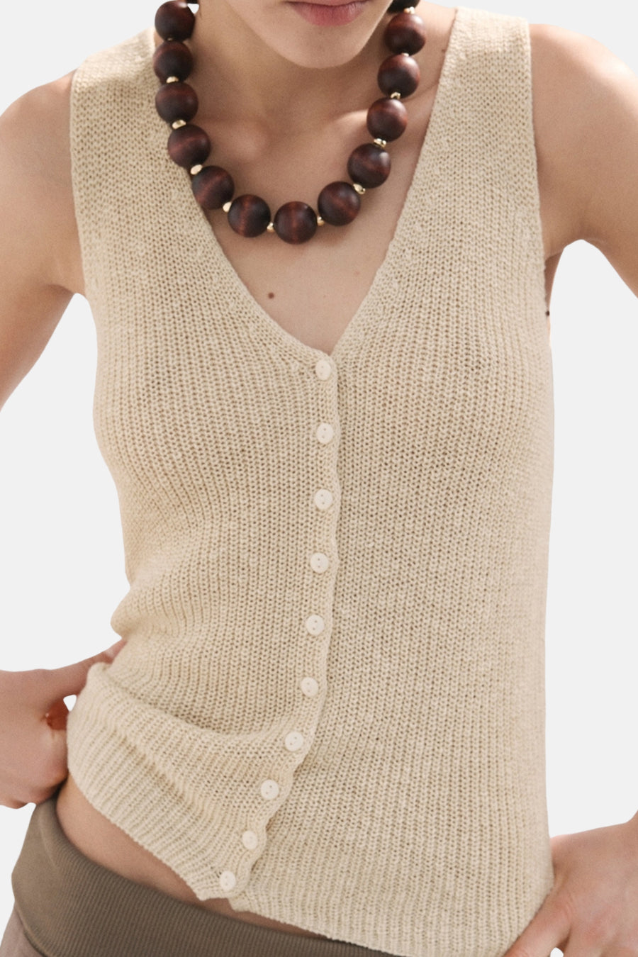 Beige top zonder mouwen van MANGO, met knoopsluiting, gebreide textuur en houten kralenketting.