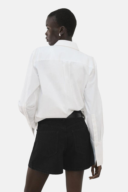 Zwarte short van MANGO, gezien van achteren met een wit overhemd en riem.