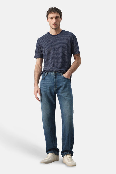 T-shirt bleu à manches courtes de MANGO, à motif rayé, porté avec un jean et des baskets.